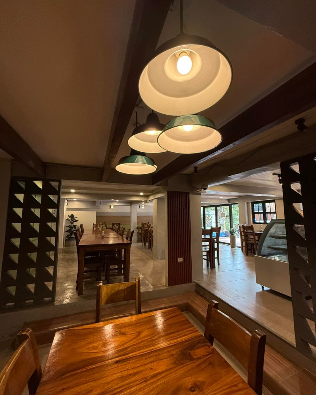 Lula's dining room — long solid-wood tables under industrial pendants, the room ready for salo-salo